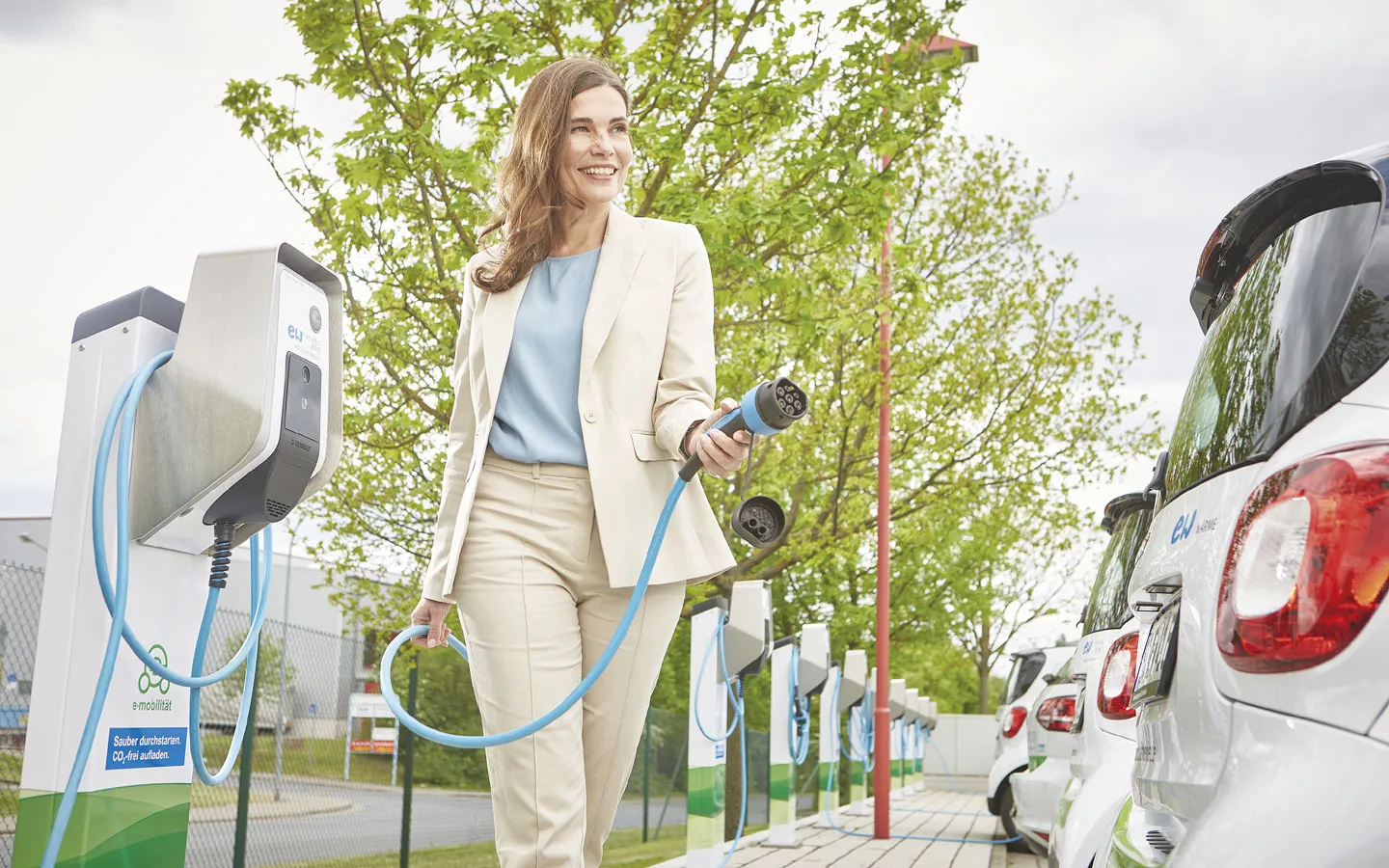 E-Mobilität - Kundin vor Ladestation mit Stecker in der Hand · Finke Elektro
